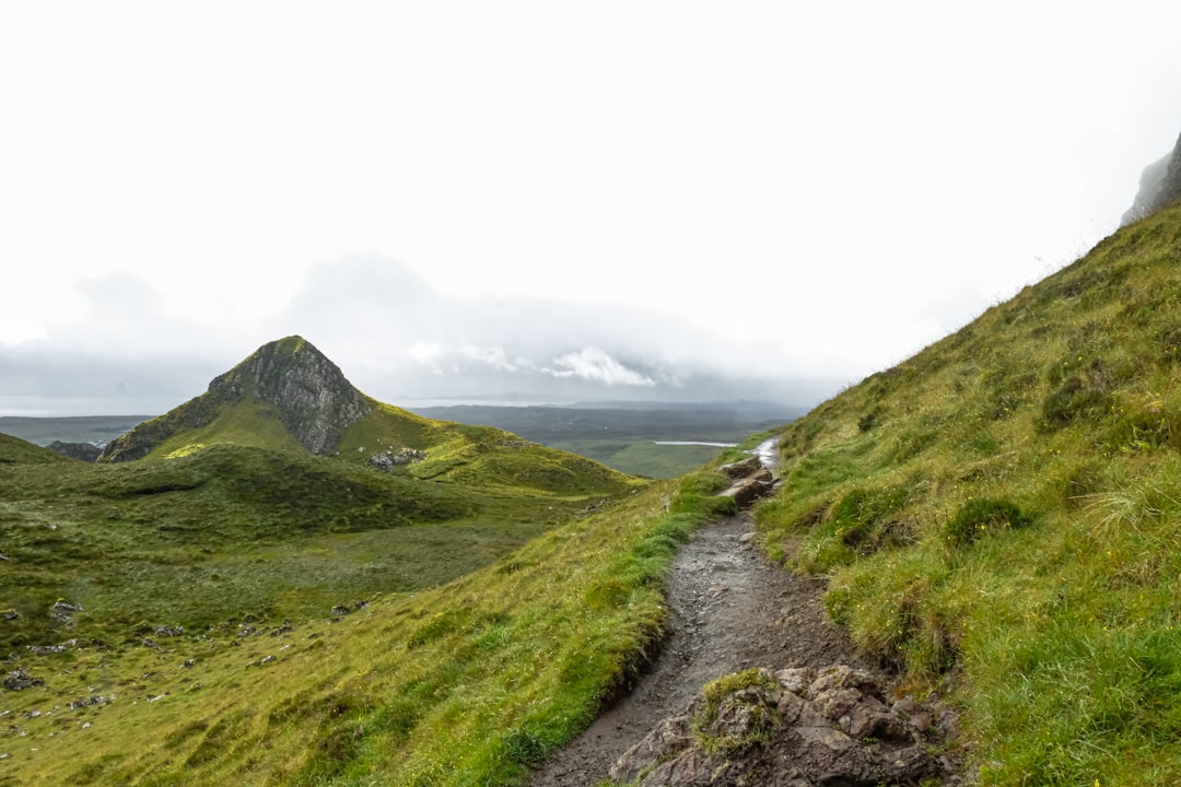 Trail runner ascending a rugged mountain path through Scottish Highlands moorland